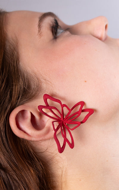 Jeune femme aux cheveux attachés avec jolie bijou rouge florale à l'oreille.