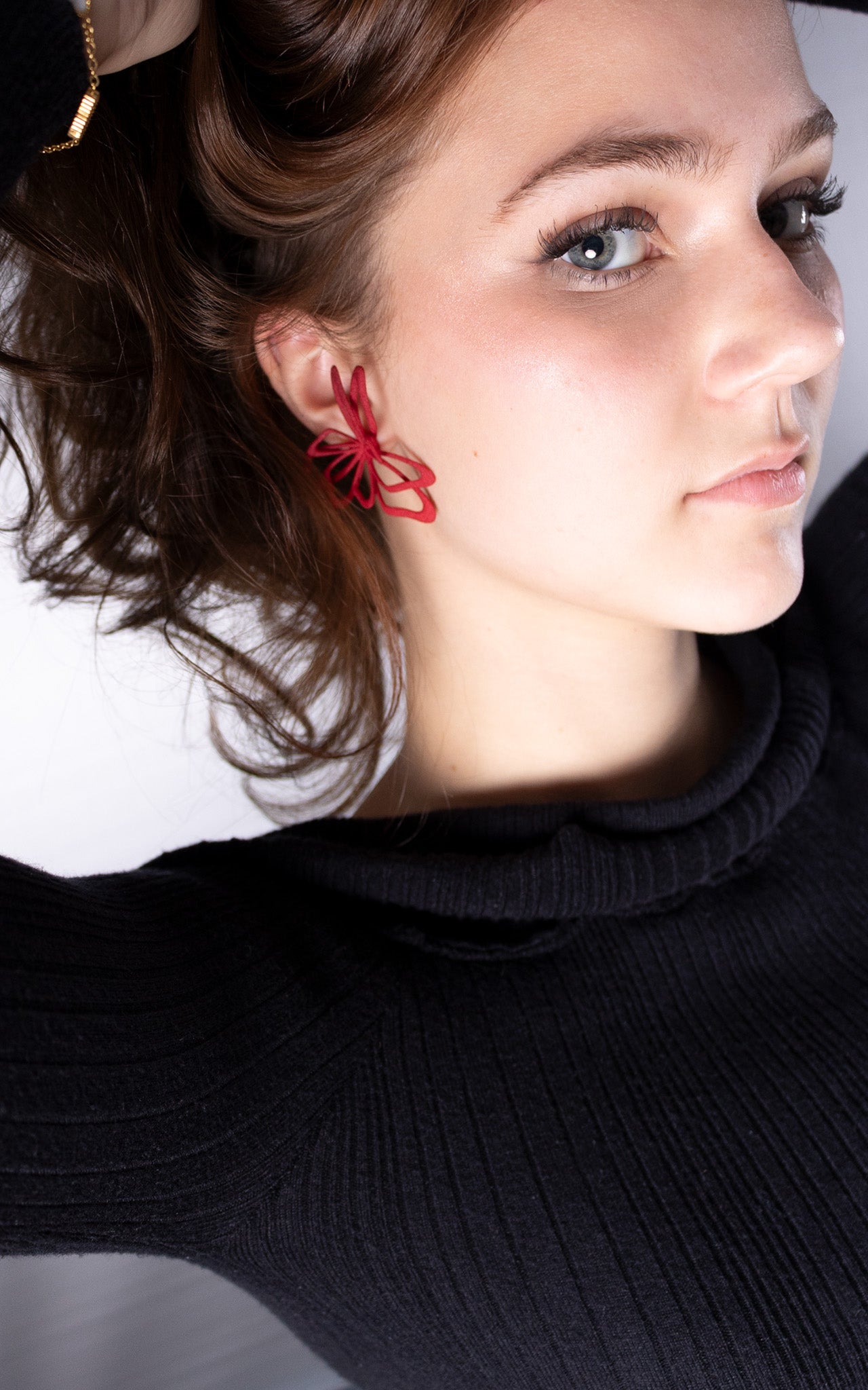 Jeune femme aux cheveux attachés avec jolie bijou rouge florale à l'oreille.