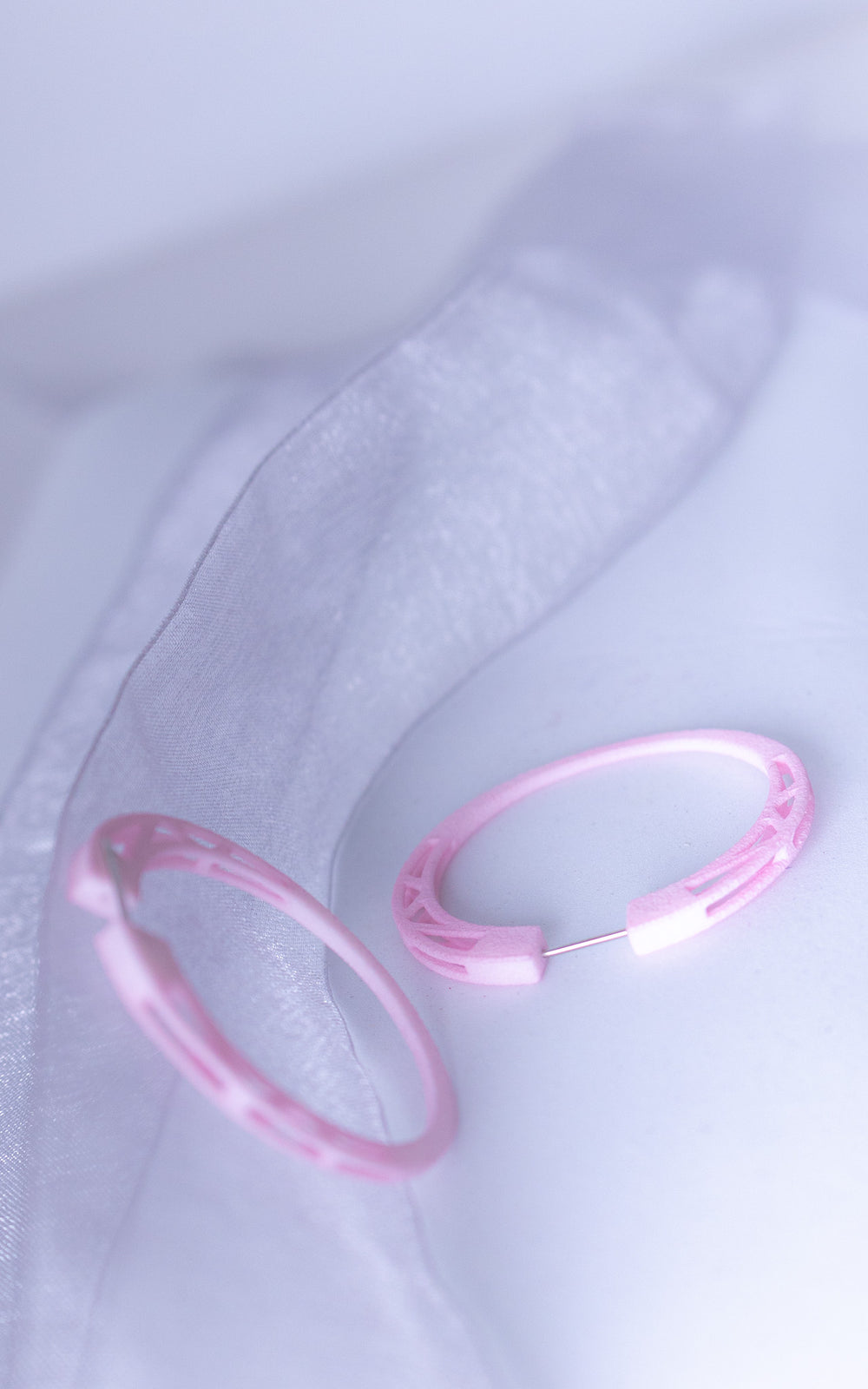 Anneaux COSMOS  rose vue détail   à structure ajourée, boucles d’oreilles architecturales légères mises en scène avec ombres graphiques