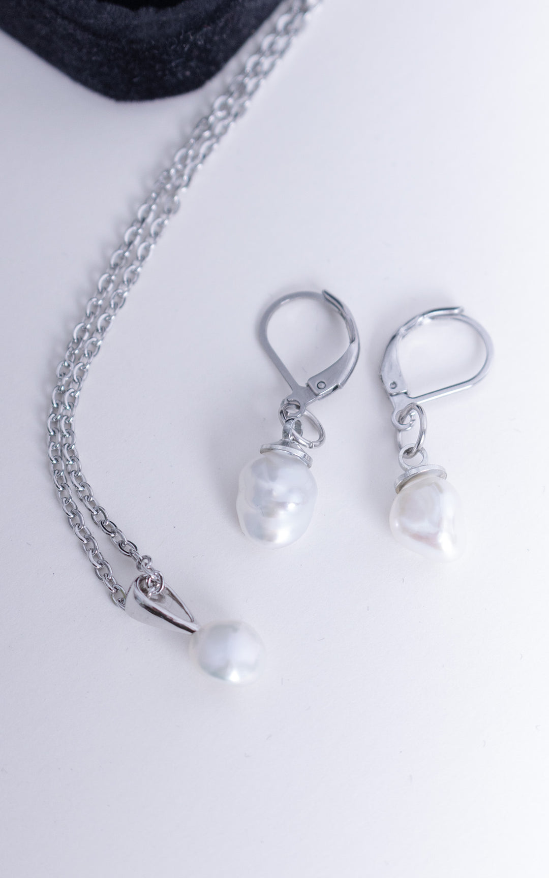 Ensemble collier et boucles d’oreilles en acier inoxydable avec perles baroques blanches, bijou minimaliste et élégant sur fond clair